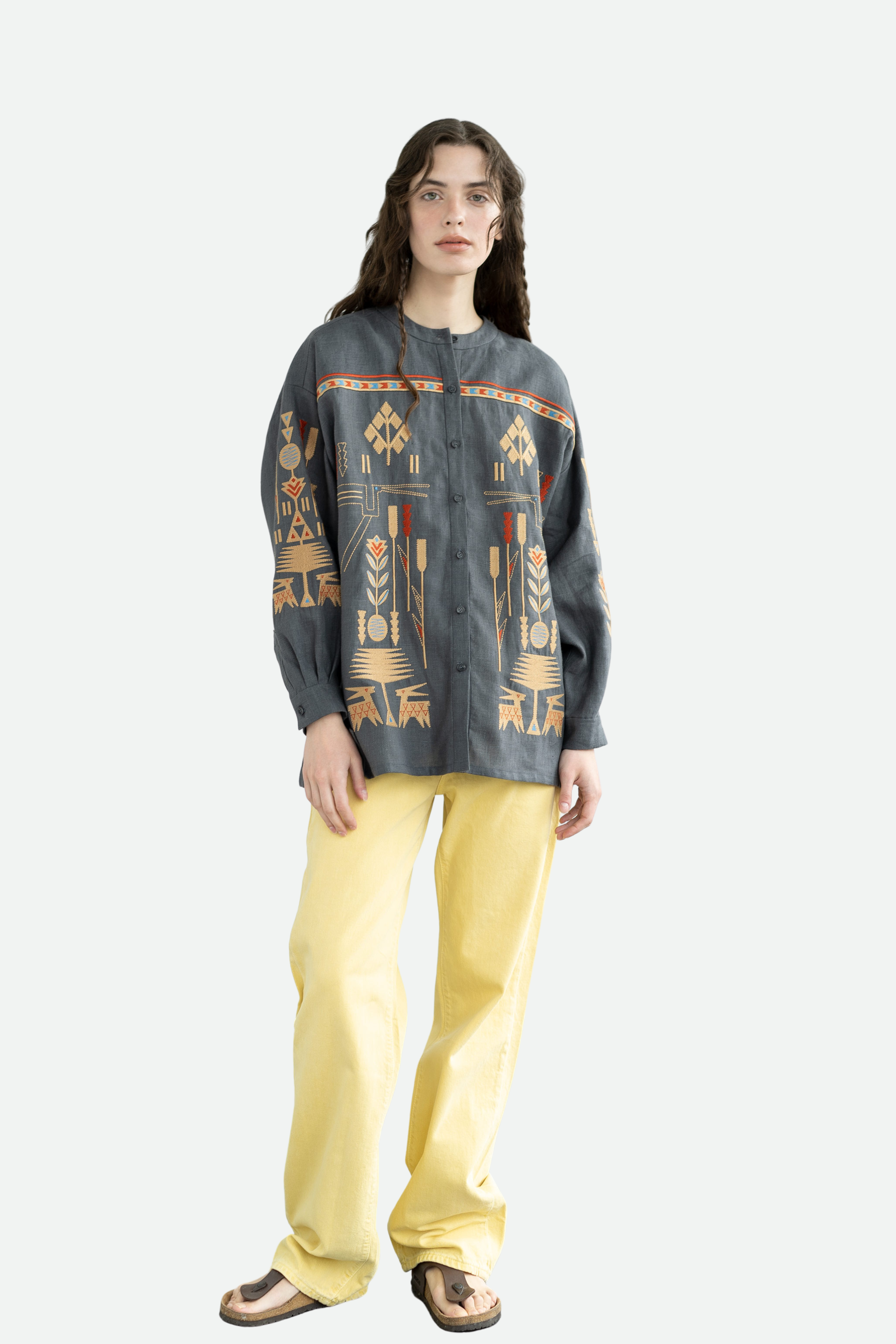 Person wearing a dark patterned sweater and yellow pants on a white background