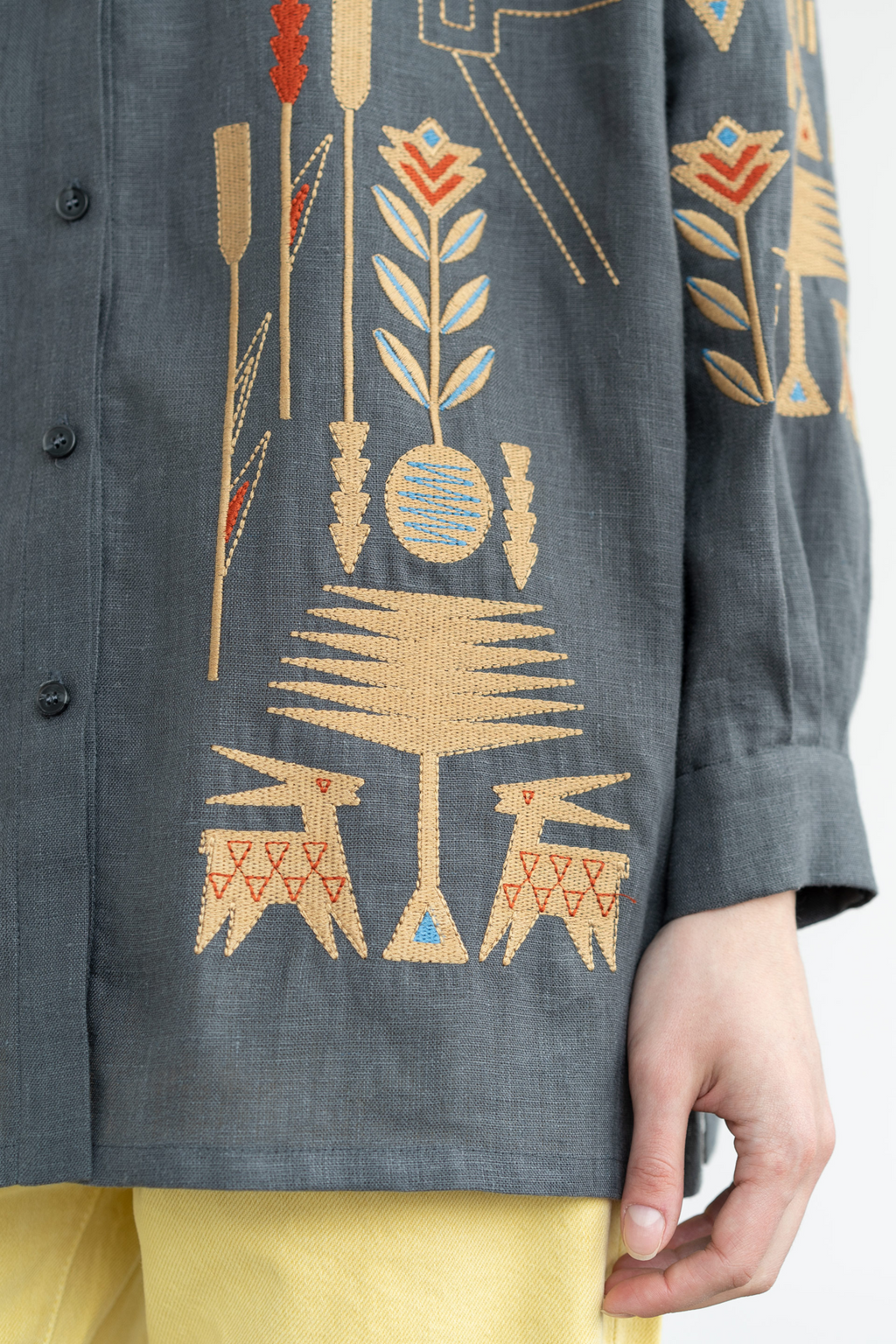 Embroidered garment with floral and abstract patterns on a plain background