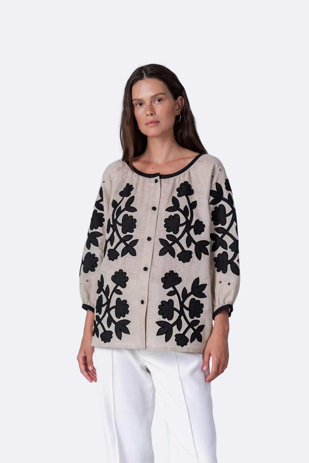 Woman wearing a beige cardigan with black floral patterns on a white background