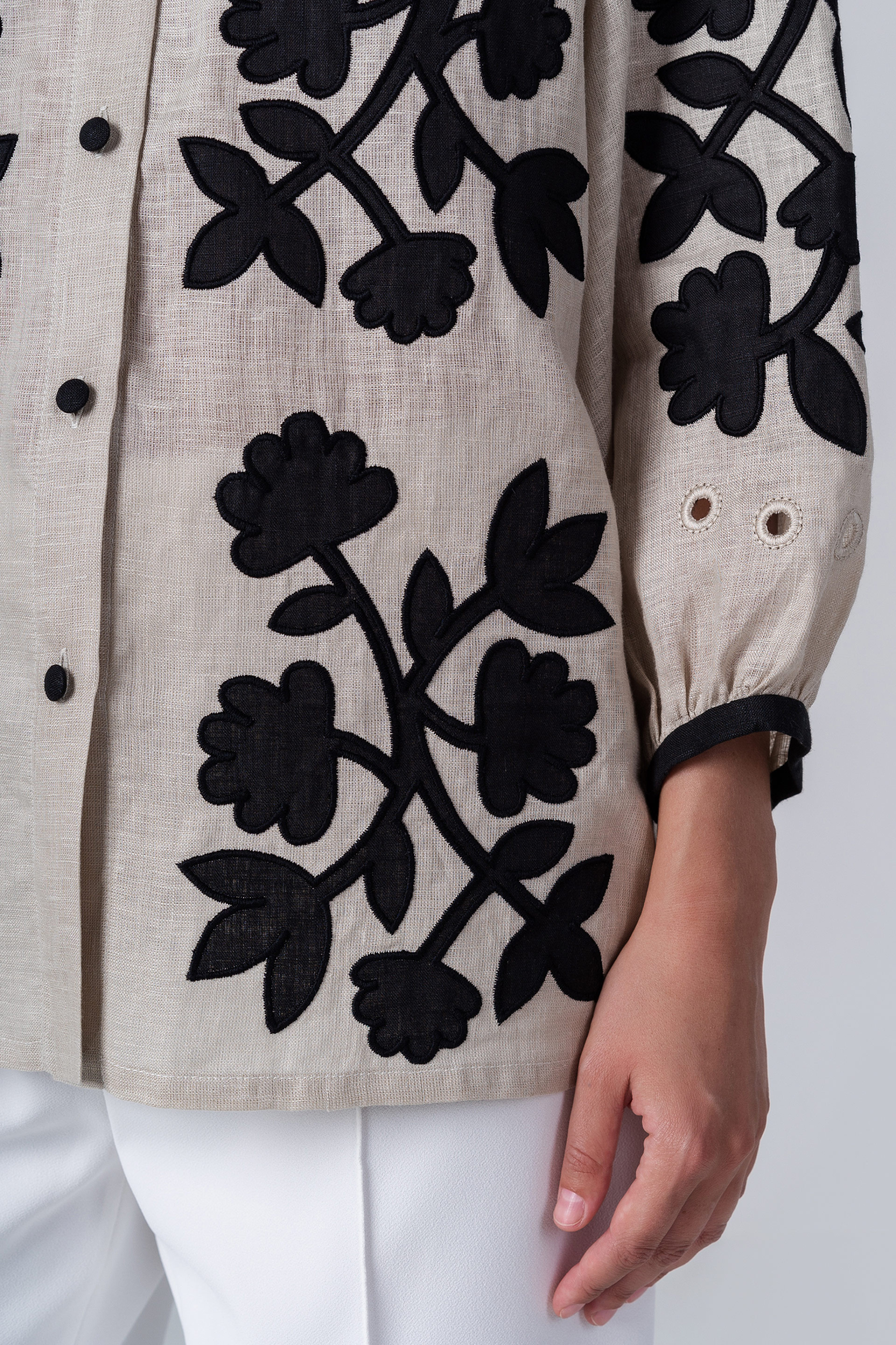 Beige jacket with black floral patterns on a white background