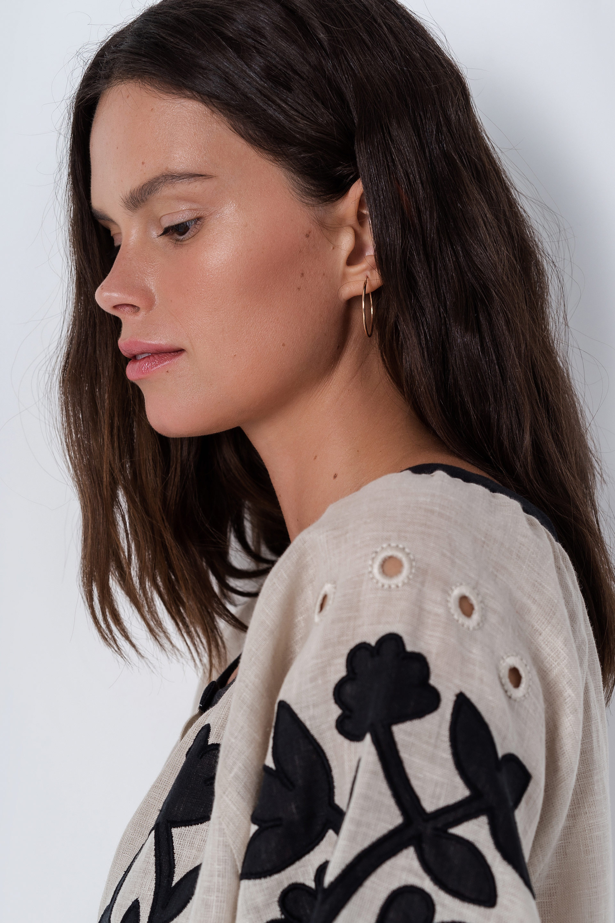 Woman wearing a beige cardigan with black floral patterns on a white background