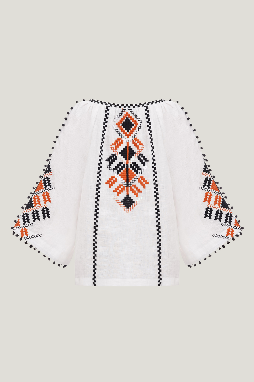 White blouse with black and orange geometric patterns on a light gray background