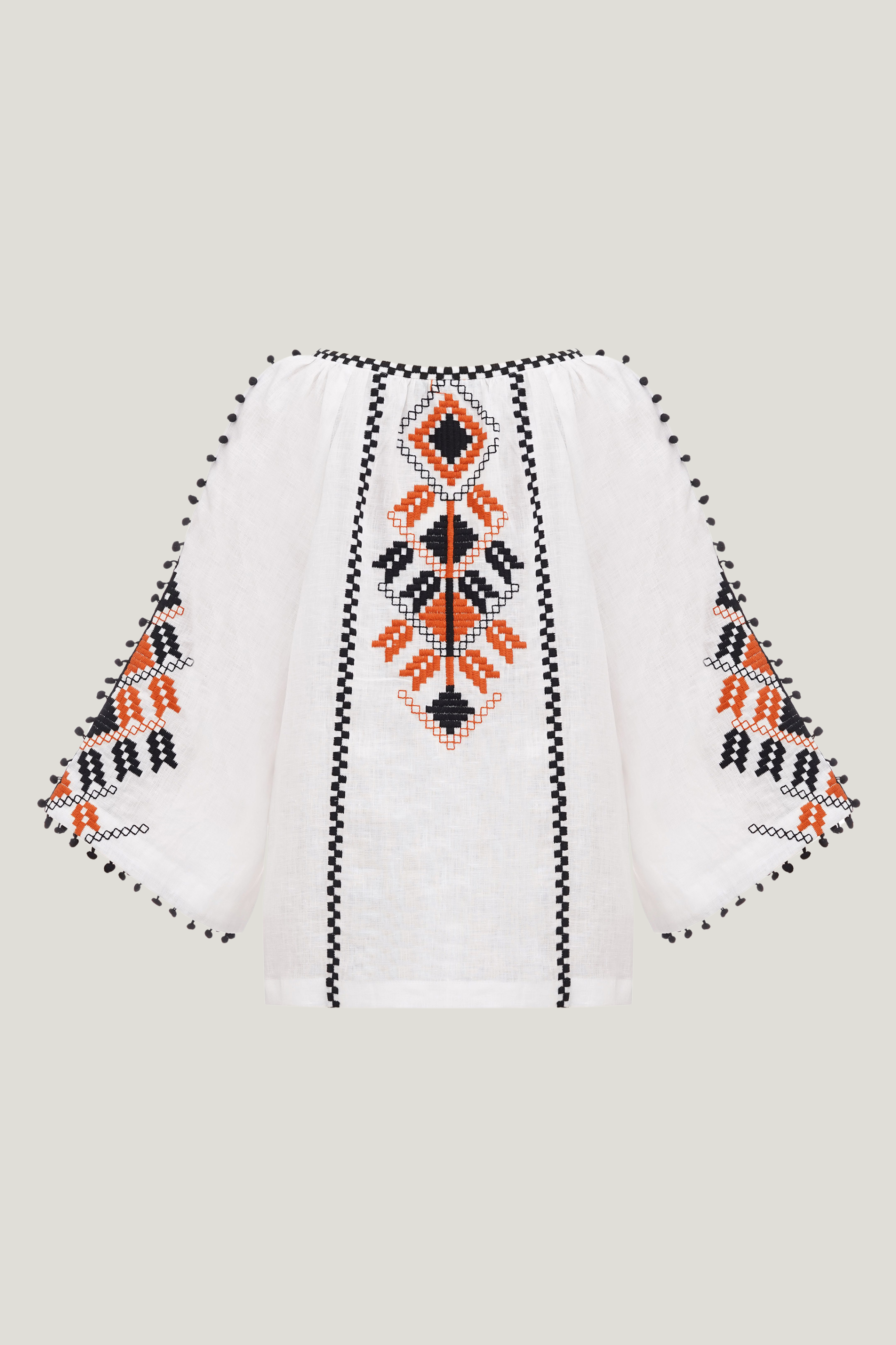 White blouse with black and orange geometric patterns on a light gray background