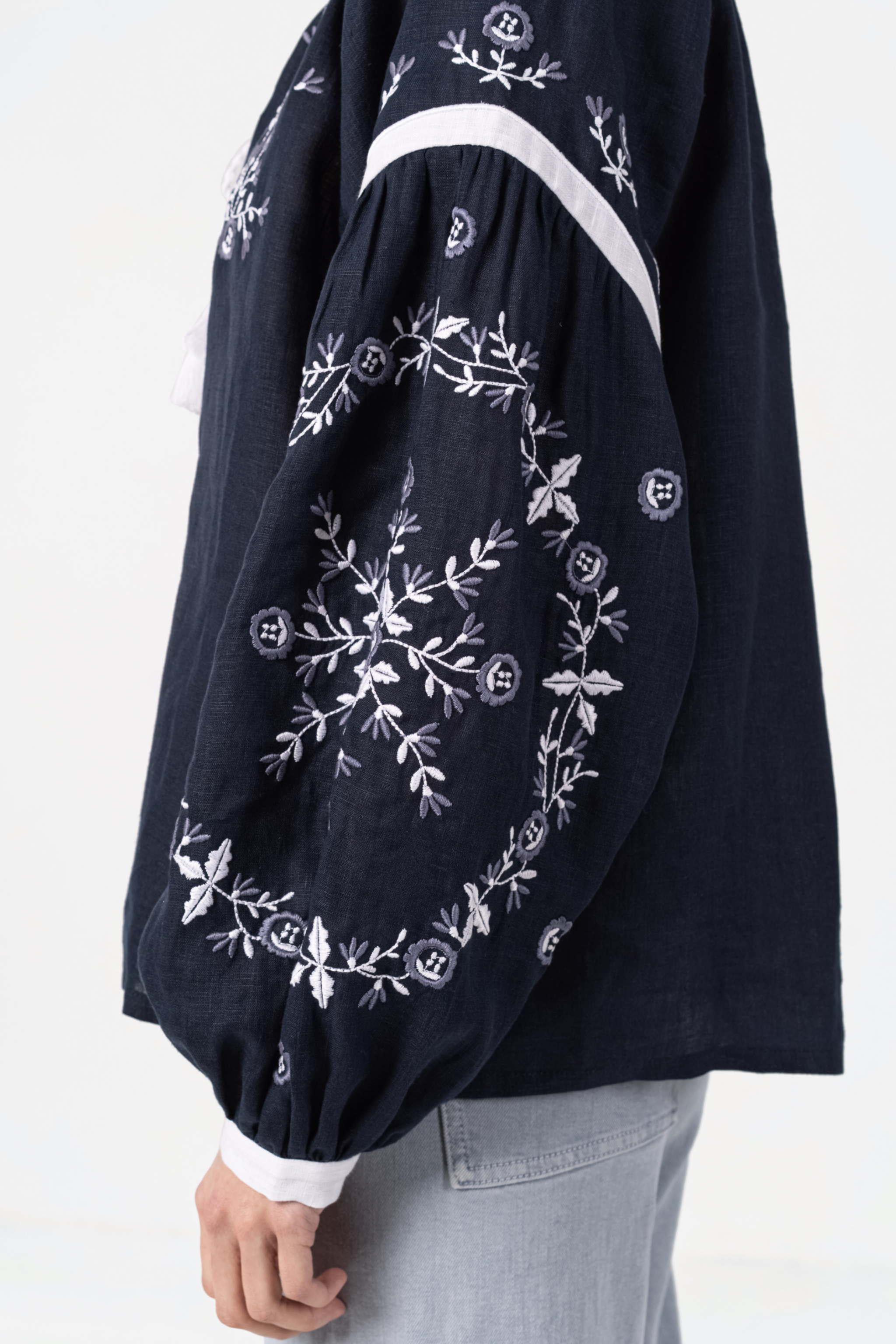 Navy blue embroidered blouse with white floral patterns on a white background